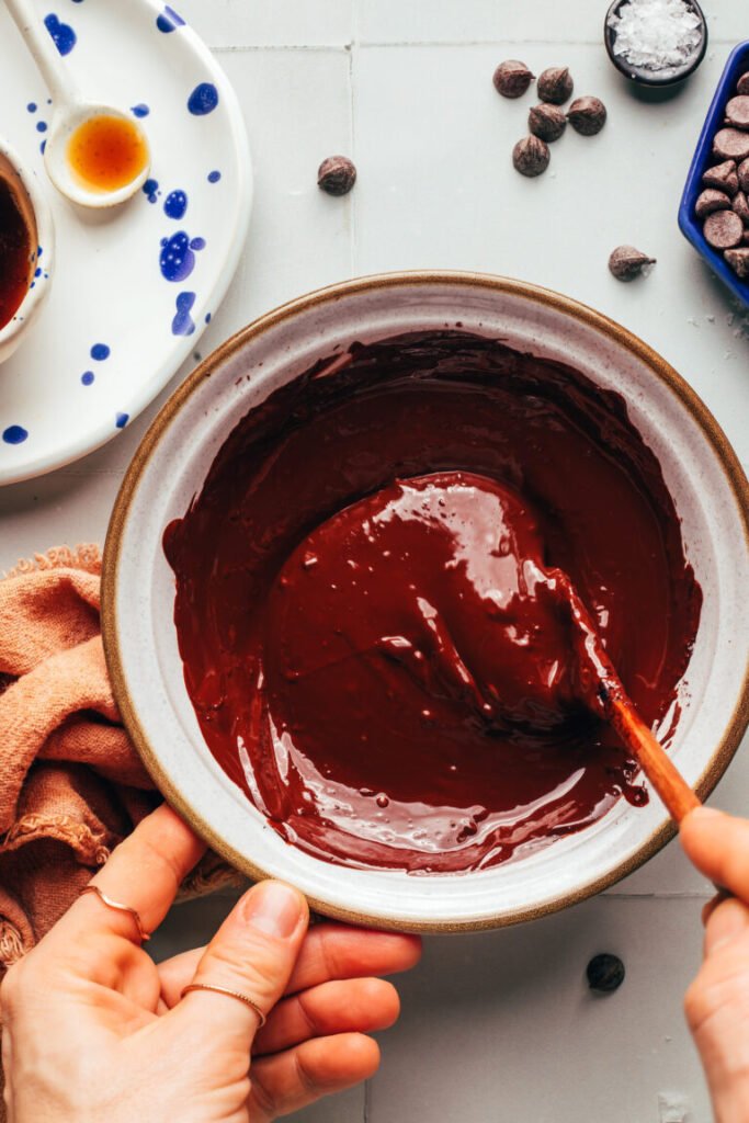 Mexendo chocolate amargo derretido em uma tigela de cerâmica