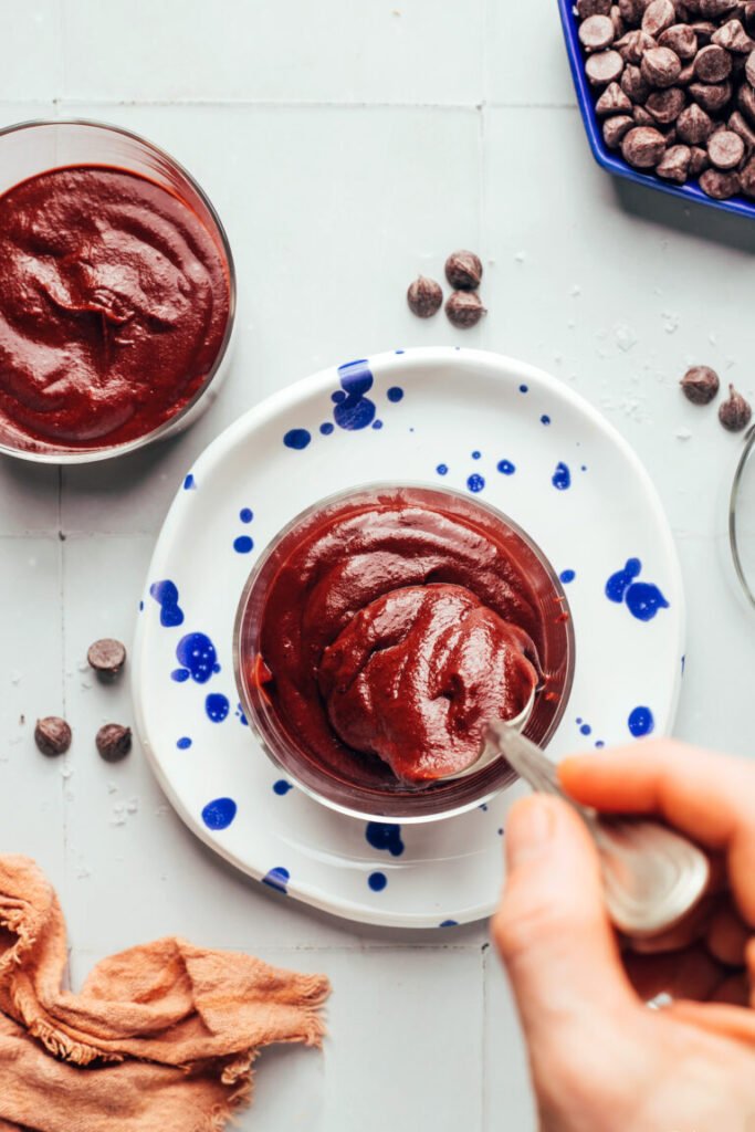 Usando uma colher para transferir o creme de batata-doce com chocolate para copos