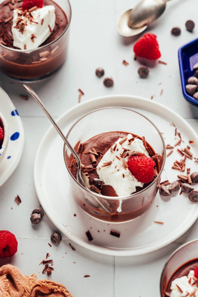 Copos de creme de leite gelado sem lactose, cobertos com chantilly de coco e framboesas frescas